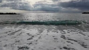 Yumuşak dalgalar kumlu sahil bulutlu kış günü Bogliasco köyüne akıyor..