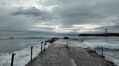 Titreyen okyanus, bulutlu kış gününde Bogliasco kıyılarındaki iskeleyi tehdit ediyor..