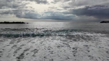 Yumuşak dalgalar, kışın sahil köyü Bogliasco 'da kumlu plajlara ağır çekim 120 fps hızla akıyor.