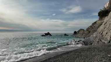 Yumuşak dalgalar kayalık kıyıları silip süpürüyor Bogliasco İtalya mavi suları