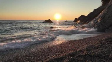 Altın gün batımı yansımaları dalgaların üzerinde parıldıyor kumlu kıyıları silip süpüren Bogliasco İtalya yavaş çekim 120fps