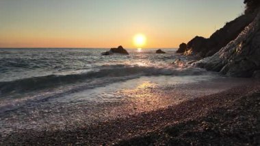 Altın gün batımı yansımaları dalgaların üzerinde parıldıyor kumlu kıyıları silip süpüren Bogliasco İtalya yavaş çekim 120fps