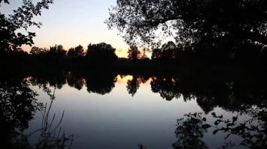 Bahar gölü manzarası, Regensburg Almanya yakınlarındaki sakin sulara mükemmel yansıyan ağaçları gösteriyor.