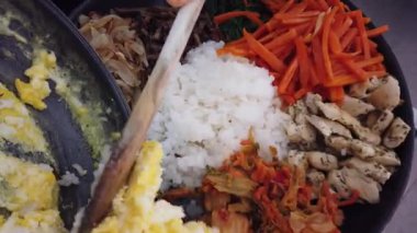 Geleneksel Kore bibimbap yemeği pişirirken renkli sebze ve pirinci bir tavada karıştırmak