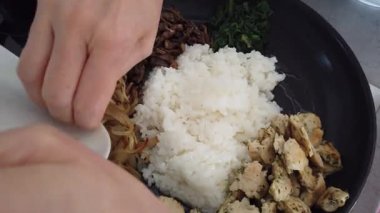 Geleneksel Kore bibimbap yemeği pişirirken renkli sebze ve pirinci bir tavada karıştırmak