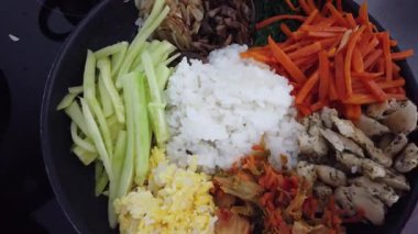 Geleneksel Kore bibimbap yemeği pişirirken renkli sebze ve pirinci bir tavada karıştırmak