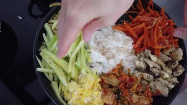 Geleneksel Kore bibimbap yemeği pişirirken renkli sebze ve pirinci bir tavada karıştırmak