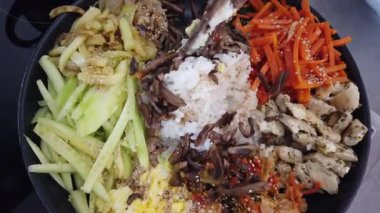 Geleneksel Kore bibimbap yemeği pişirirken renkli sebze ve pirinci bir tavada karıştırmak