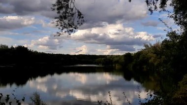 Altın güneş, Regensburg yakınlarındaki sakin göl suyuna yansıyan orman siluetlerinin ardında batıyor.