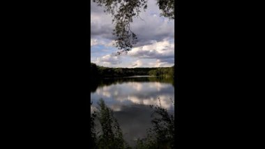Altın güneş, Regensburg yakınlarındaki sakin göl suyuna yansıyan orman siluetlerinin ardında batıyor.