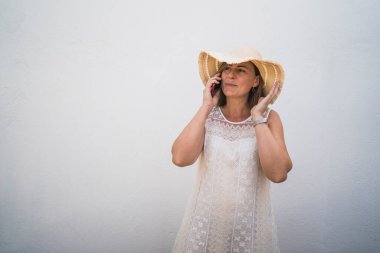 Telefonunu ve kulaklığını şapka takan bir kadın.