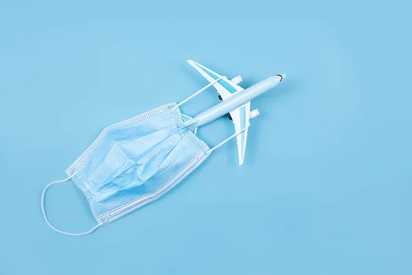 Airplane in flight with a medical mask. Concept - observance of safety on the plane. Traveling by air at social distance. Compliance with the recommendations of doctors on trips. Opening borders.
