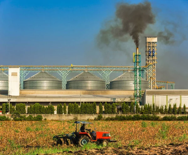 农业筒仓 烟道排放的浓烟污染大气 而农场的跟踪器在前方移动 — 图库照片#