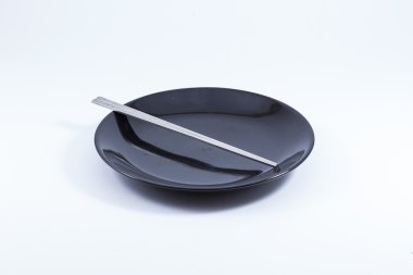 Siyah seramik plaka üzerinde gümüş yemek çubukları. (Beyaz bac izole