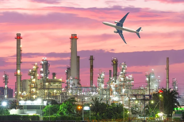 Airplane flying over oil refinery industry plant along twilight — Stock Photo, Image