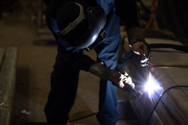 Metal işçileri amelelik, becerikli kaynakçılık, fabrika işçileri OT yapıyor. Kaynakçı fabrikadaki çeliği kaynaklıyor..