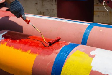 Fabrikadaki paslanmaz boyalı çelik borular. Kırmızı demir boru. Paslanmaz boya, su boruları.