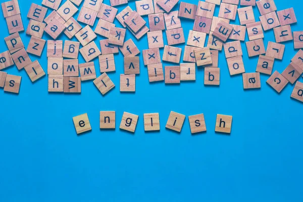 青い背景に散在英語のアルファベットと正方形の木製のタイルで作られた英語のアルファベット 思考の発達文法の概念 — ストック写真