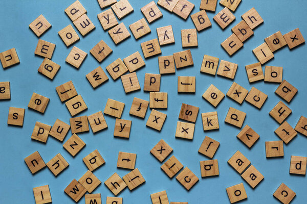 English alphabet made of square wooden tiles with the English alphabet scattered on blue background. The concept of thinking development,grammar.