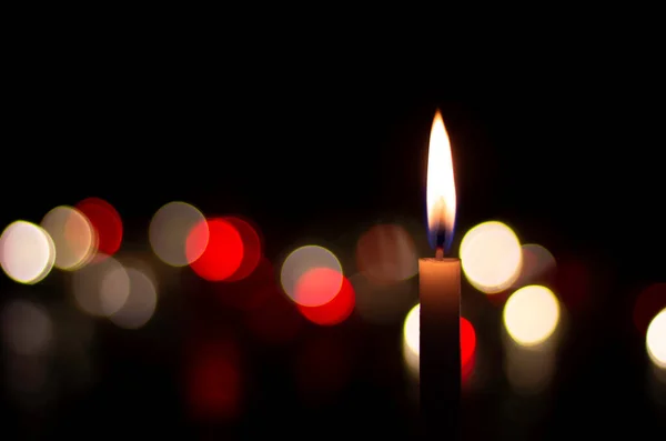 Mum alevi sarı bokeh arkaplanı bulanıklaştırdı. Siyah arkaplanda bir mum yak.