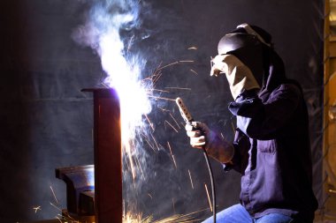 Becerikli kaynakçılar fabrikada çelik kaynak yapar. İnşaat alanı metal kaynakçısı. İnşaatçılar iş yerinde güvenlik için yangın geçirmez eldiven giyerler..