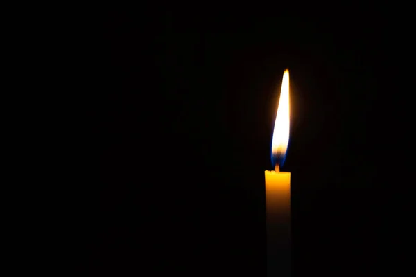 Mum alevi arkaplanı bulanıklaştırdı. Siyah arkaplanda bir mum yak.