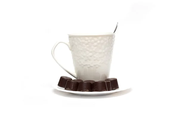 Chocolates en plato blanco junto a tazas. Foto: . — Foto de Stock