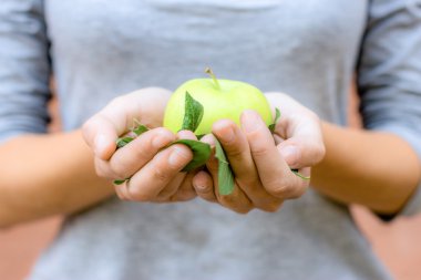 Ellerinde yaprakları ile yeşil elma.