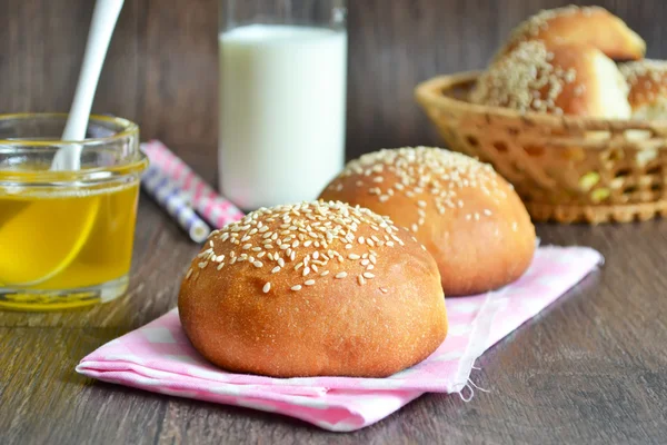 Homemade buns with sesame seeds and milk for breakfast — Stock Photo, Image