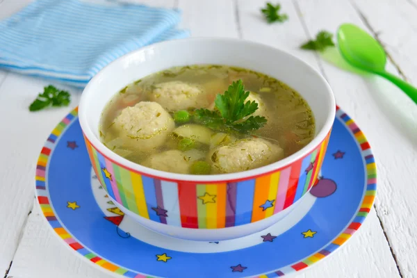 Light soup with meatballs and green peas, dinner for children