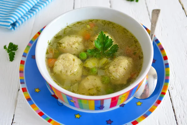 Light soup with meatballs and green peas, dinner for children