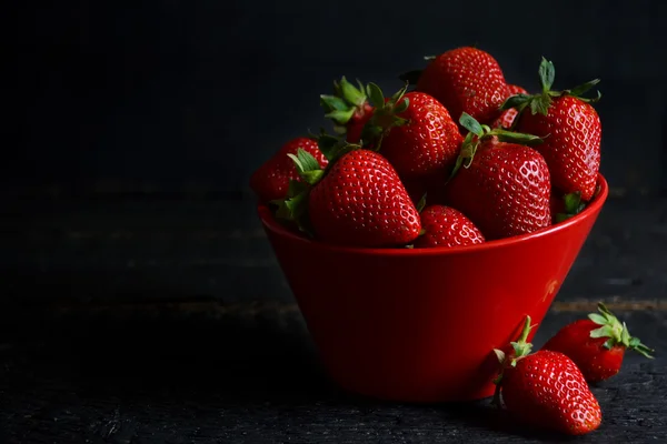 Juicy, fresh strawberries in a dish on a black background — Stock Photo, Image