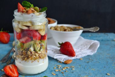 Yulaf ezmesi yoğurt, kivi, muz, çilek ve badem içinde bir