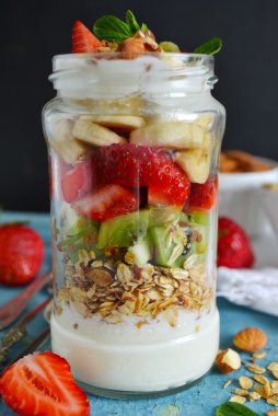 Yulaf ezmesi yoğurt, kivi, muz, çilek ve badem içinde bir