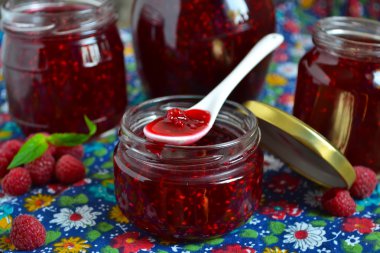 Ahşap arka plan üzerinde bir cam kavanoza taze frambuaz reçeli