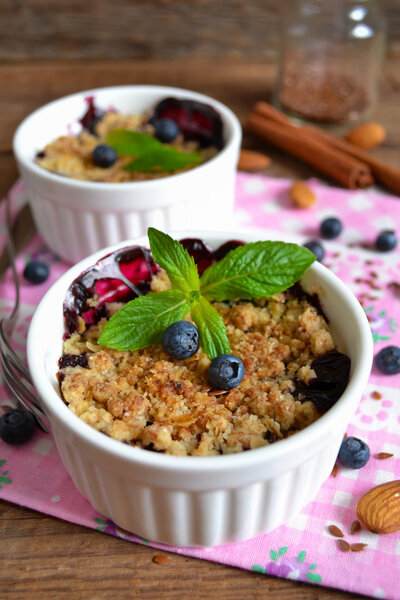 Berry crumble with oatmeal and almonds on wooden background