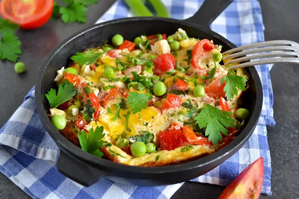 Frittata with tomatoes, peppers, green peas and feta cheese in a — Stock Photo, Image