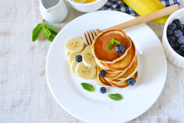 Small pancakes stacked with blueberries, banana and honey — Stock Photo, Image