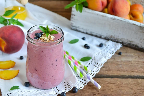 Smoothie de pêssego, banana e mirtilos com aveia em uma madeira — Fotografia de Stock