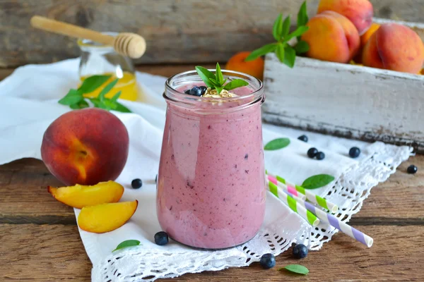 Smoothie de pêssego, banana e mirtilos com aveia em uma madeira — Fotografia de Stock