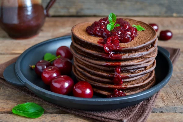 Schokoladenpfannkuchen mit Beerenmarmelade zum Frühstück auf einem hölzernen Rücken — Stockfoto