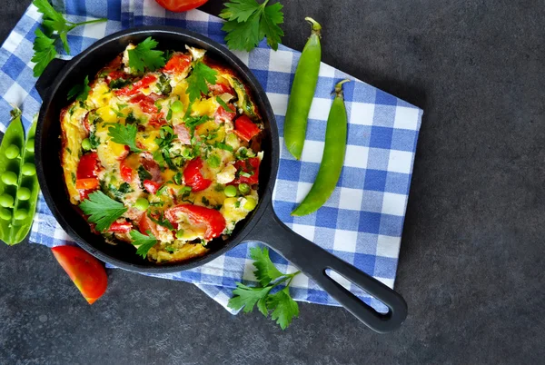 Frittata med tomater, paprika, gröna ärtor och fetaost i en — Stockfoto