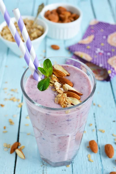 Batido con arándanos y almendras en un vaso sobre un respaldo azul — Foto de Stock