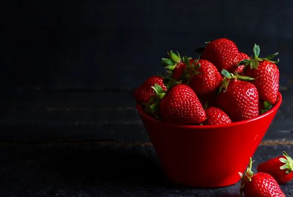 Juicy, fresh strawberries in a dish on a black background — Stock Photo, Image