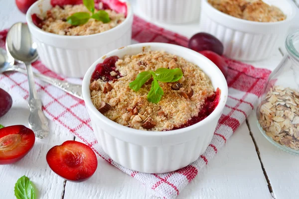 Oat crumble with plums, spices and honey on a light background — Stock Photo, Image