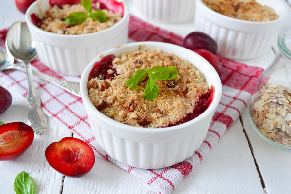 Oat crumble with plums, spices and honey on a light background