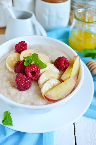 Farina d'avena porridge con miele, banana, lamponi e pesche per — Foto Stock