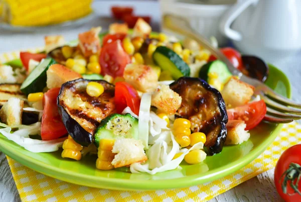 Salad with corn, tomatoes, eggplant and grilled croutons on a co