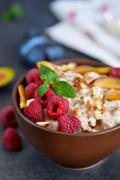 Овсянка с ягодами, сливами, орехами и медом на завтрак — стоковое фото