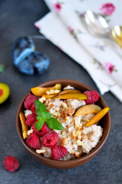 Овсянка с ягодами, сливами, орехами и медом на завтрак — стоковое фото